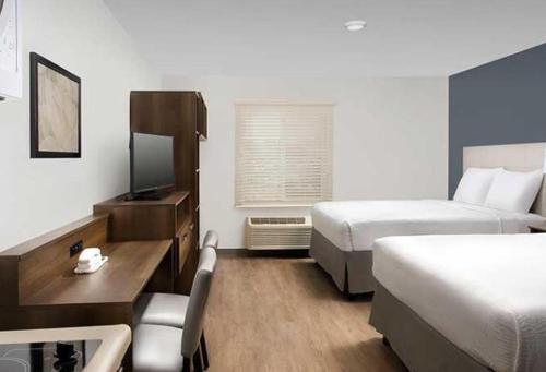 ein Hotelzimmer mit 2 Betten und einem Schreibtisch in der Unterkunft WoodSpring Suites Littleton-South Denver in Littleton