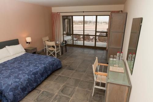 a bedroom with a bed and a table and a window at Azraq Lodge in Al Azraq ash Shamālī