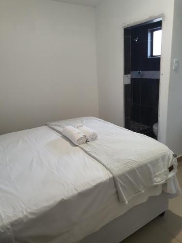 a bedroom with a white bed with towels on it at BF Dlamini Guest House in Amanzimtoti
