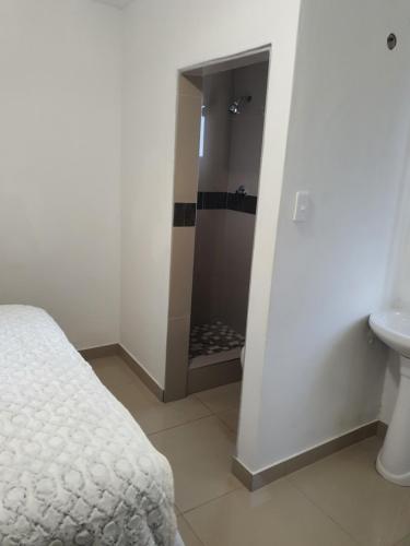 a bathroom with a shower and a bed and a sink at BF Dlamini Guest House in Amanzimtoti