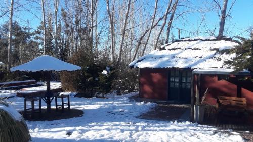 a house in the snow with a table and an umbrella at POSADA MI ESPERANZA in Cacheuta