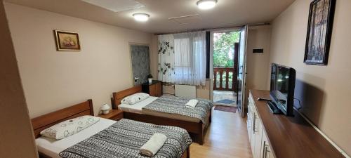 a bedroom with two beds and a tv and a window at Dworek Pokoje Gościnne in Olsztyn