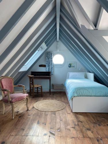 a bedroom with a bed and a desk in a attic at La Maison Bleue in Port-en-Bessin-Huppain