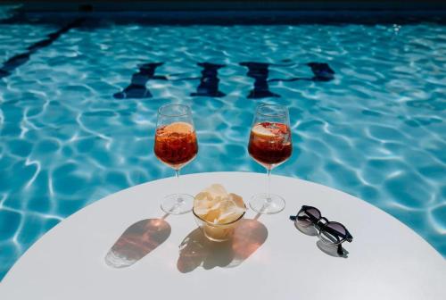 two wine glasses sitting on a table next to a pool at Hotel Villa Patriarca in Mirano