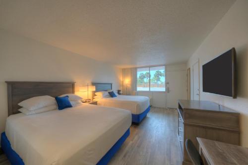 a hotel room with two beds and a flat screen tv at The Island Resort at Fort Walton Beach in Fort Walton Beach
