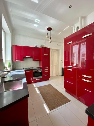 a red kitchen with black counter tops and appliances at Deluxe Downtown Apartment with a Fabulous View in Budapest