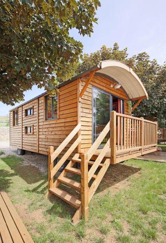 Cette petite cabane en bois dispose d'une grande véranda et d'une rampe. dans l'établissement Le Clos Du Pin, au Grand-Bornand