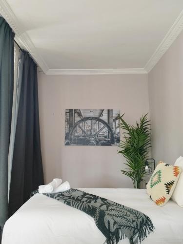 a bedroom with two beds with white sheets and a plant at Railway by Staynnapartments in Bilbao