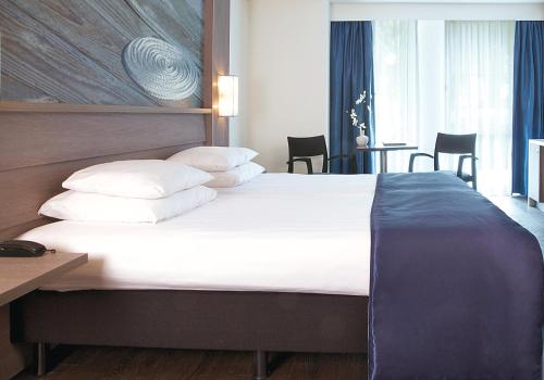 a bedroom with a large bed with white sheets and pillows at Hotel Medemblik in Medemblik