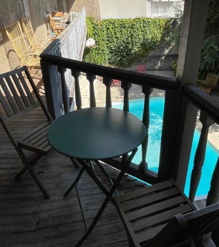 a table and chairs on a porch with a pool at La Maison aux murs anciens et ses chambres in Tarbes