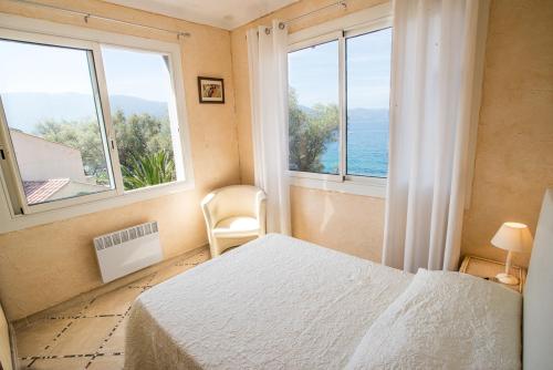 a bedroom with a bed and two large windows at Résidence Villa Nova in Tiuccia