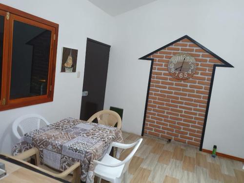 a room with a table and a brick wall with a clock at Casa Blanca Suites in Puerto López