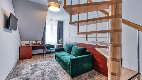a living room with a green couch and a spiral staircase at St Lukas Medical & SPA in Świeradów-Zdrój