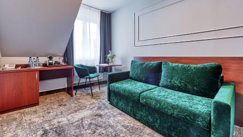 a living room with a green couch and a desk at St Lukas Medical & SPA in Świeradów-Zdrój