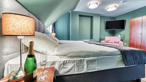 a bedroom with a bed with a bottle of wine on a table at St Lukas Medical & SPA in Świeradów-Zdrój