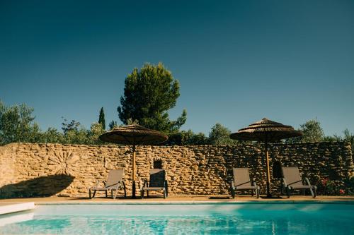 a group of chairs and umbrellas next to a pool at Clos Saint-Michel Resort & Spa in Malaucène