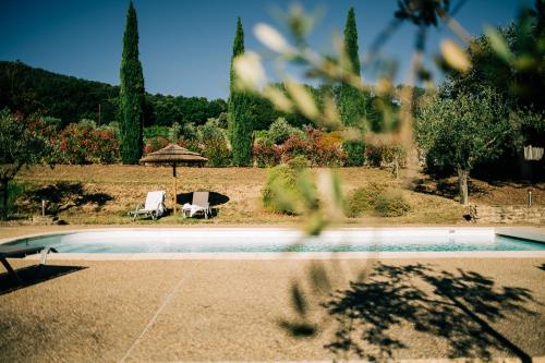 a swimming pool with two chairs and an umbrella at Clos Saint-Michel Resort & Spa in Malaucène