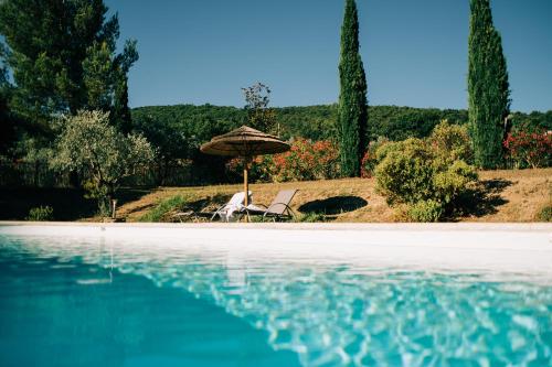 a pair of chairs and an umbrella next to a swimming pool at Clos Saint-Michel Resort & Spa in Malaucène