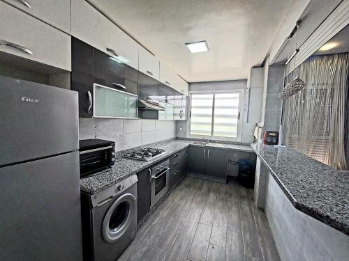 una cucina con piano cottura, lavatrice e asciugatrice di Appartement Agadir ad Agadir