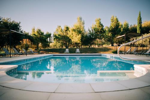 a swimming pool in a yard with chairs and trees at Clos Saint-Michel Resort & Spa in Malaucène