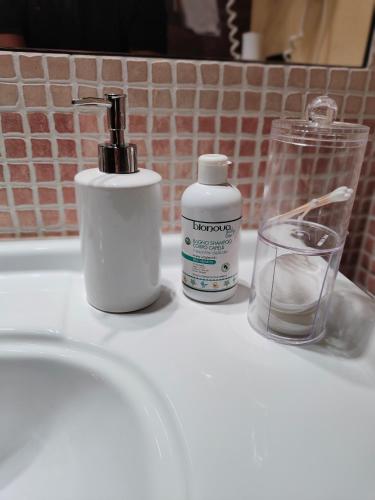 a white sink with a bottle of soap and a glass at CASA DUCHESSE al Castello in Ferrara