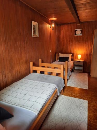 two beds in a room with wooden walls at Rest House Korana in Karlovac