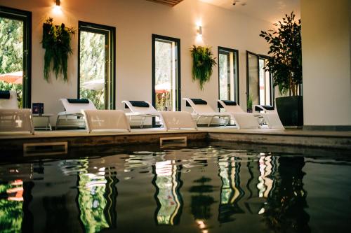 a swimming pool with white chairs and a pool of water at Clos Saint-Michel Resort & Spa in Malaucène