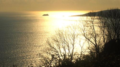 a sunset over a body of water with a island at Beautiful Seaside one bedroom apartment in Shaldon