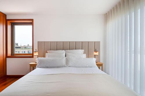 Un dormitorio con una gran cama blanca y una ventana en Leça Front Beach Luxury Penthouse, en Leça da Palmeira