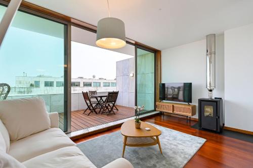 a living room with a white couch and a table at Leça Front Beach Luxury Penthouse in Leça da Palmeira