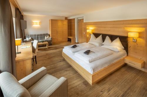 a bedroom with a large bed and a living room at Hotel Sella***s in Selva di Val Gardena