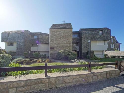 un bâtiment avec une clôture devant lui dans l'établissement Spacieux studio terrasse, mer à 700m commerces, parking privé, Wi-Fi inclu - FR-1-349-116, à Larmor-Plage