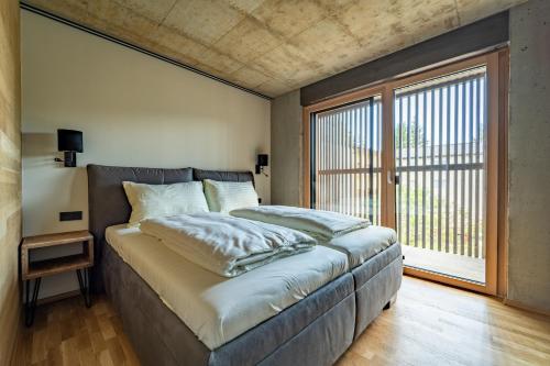 um quarto com uma cama e uma grande janela em Merlrose Apartments em Sankt Kanzian