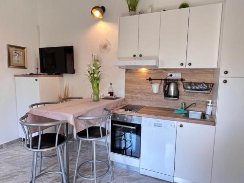 kuchnia z białymi szafkami i stołem z stołkami w obiekcie Apartments Valentinovo w mieście Klenovica