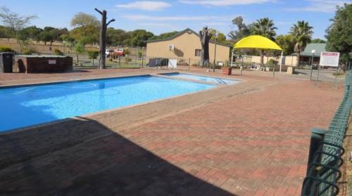 a large swimming pool with a yellow umbrella next to it at Pendleberry Holiday Resort - Unit 40 in Bela-Bela
