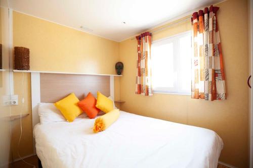 Un dormitorio con una cama blanca con almohadas amarillas y naranjas en Sunny Tiny House with Sea view en Roque