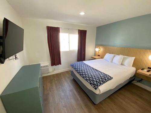 a bedroom with a bed and a flat screen tv at Salt Air Lodge in Santa Cruz