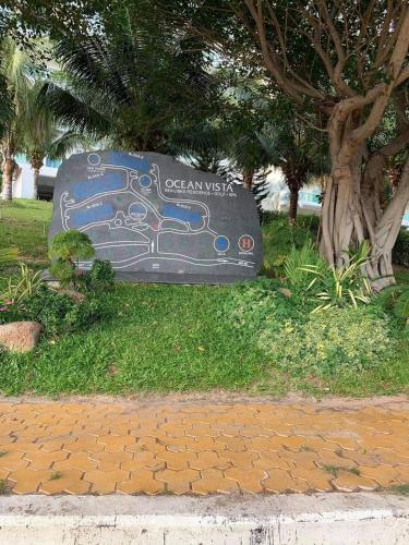 a sign in the grass next to a tree at Hotel,Căn Hộ Mũi Né Sea link in Phan Thiet
