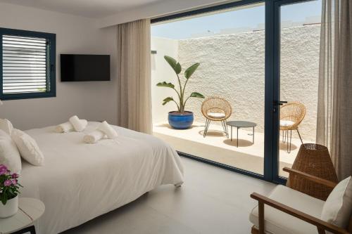 1 dormitorio con 1 cama y balcón con planta en TABOIRE by Buenavilla, en Puerto Calero