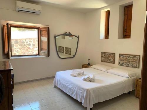a bedroom with a white bed and a mirror at Le case sul lido di Lingua - Isola Salina in Lingua