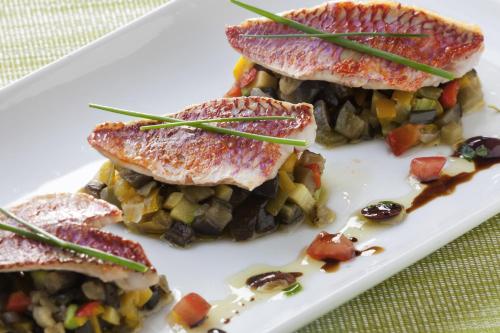 a white plate of food with fish and vegetables at Novotel Kolkata Hotel and Residences in Kolkata