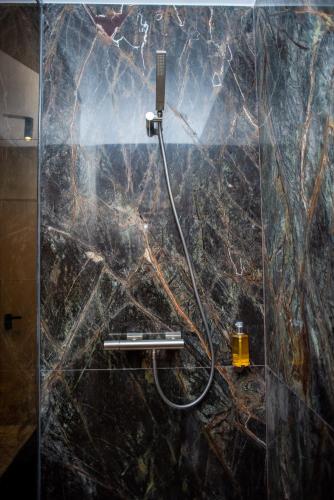 a shower with a hose on a marble wall at Opera Apartments in Cluj-Napoca