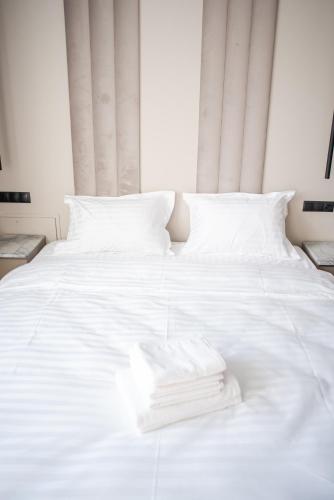 a white bed with white sheets and towels on it at Opera Apartments in Cluj-Napoca