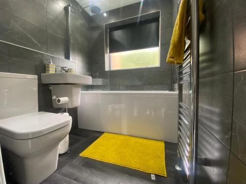 a bathroom with a white toilet and a yellow rug at Entire Luxury Holiday Home leeds in Beeston