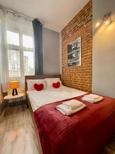 a bedroom with a large bed with a brick wall at Red&Yellow Apartments Centrum in Olsztyn