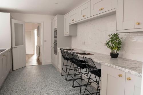 a kitchen with white cabinets and a counter with stools at The Callie by Sasco Apartments in Blackpool