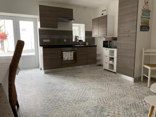 une cuisine avec des armoires en bois et une table et des chaises dans l'établissement Le saint Exupery, à Saint-Vigor-le-Grand