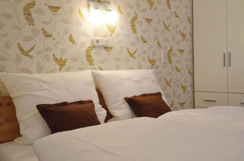 um quarto com 2 camas com lençóis brancos e almofadas castanhas em Reisekultouren Apartments Detmold em Detmold