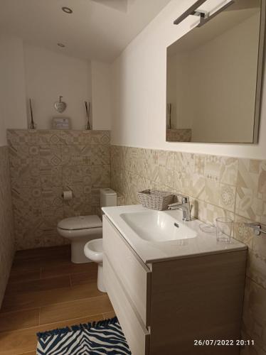 a bathroom with a sink and a toilet and a mirror at A piscaria in Catania