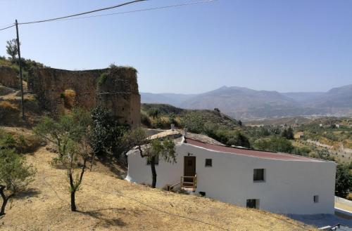 una casa bianca su una collina con montagne sullo sfondo di Molino Mio a Lúcar